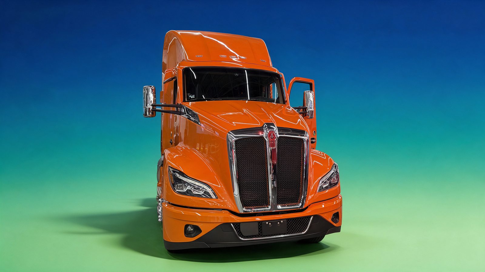 Kenworth T680 de cabina naranja en vista frontal, con la parrilla cromada y el emblema Kenworth al centro.